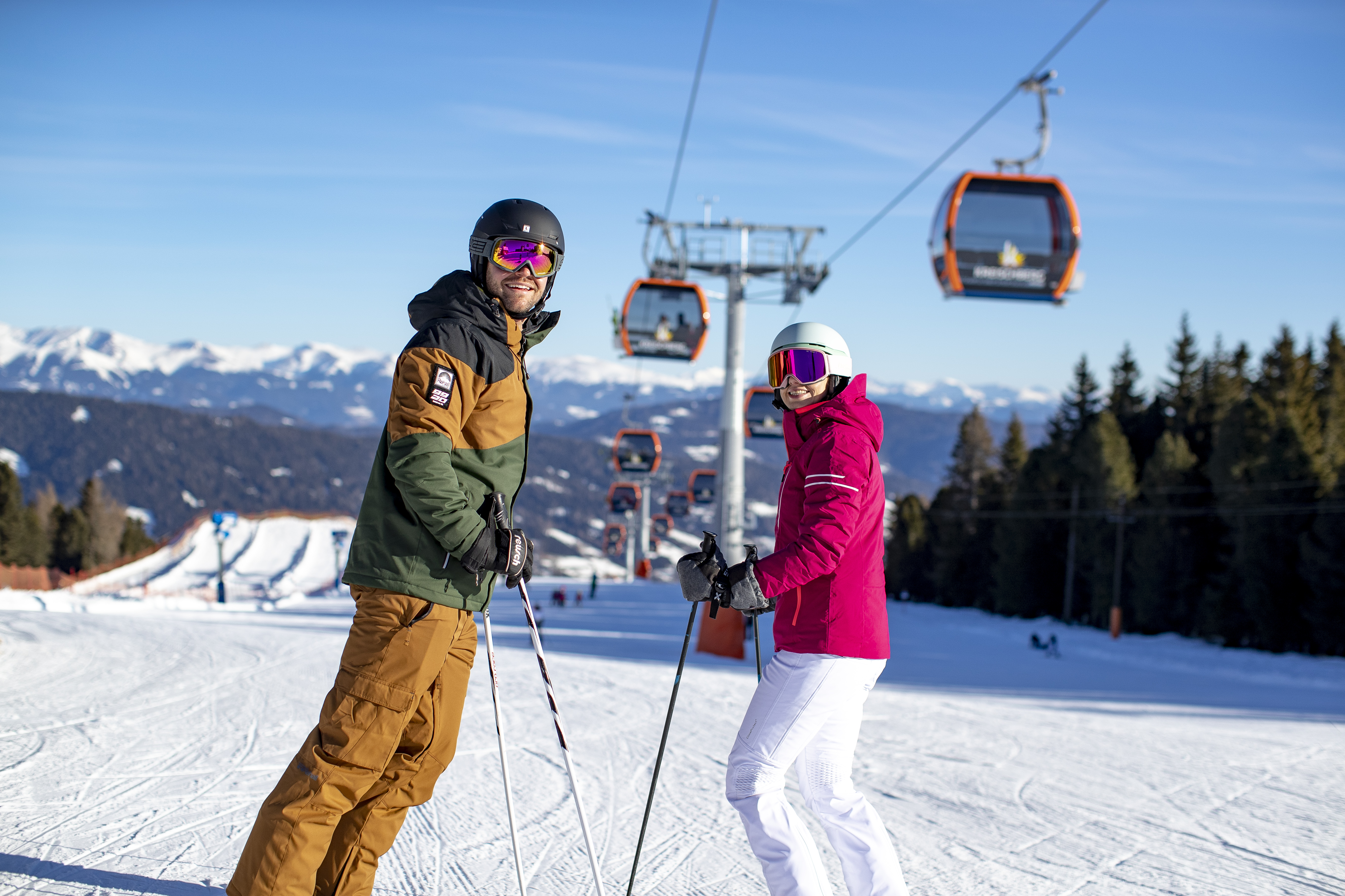 Zwei Skifahrer auf einer Piste am Kreischberg mit Gondelbahn im Hintergrund